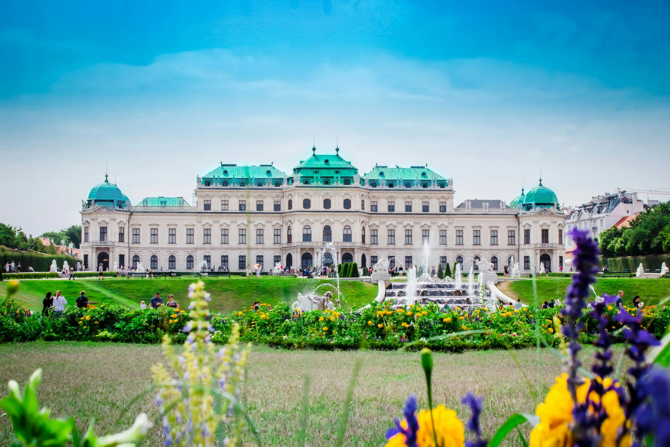 an old white building with a fountain in the middle of the lawn