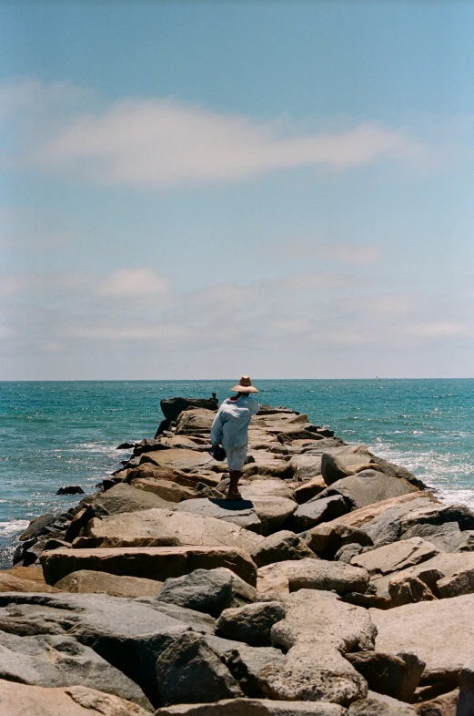 a man that is standing on rocks by the water