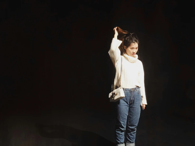 woman in white shirt and jeans with hand on head