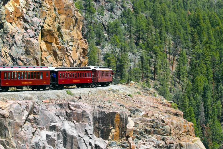 a red train traveling down tracks near large rocks