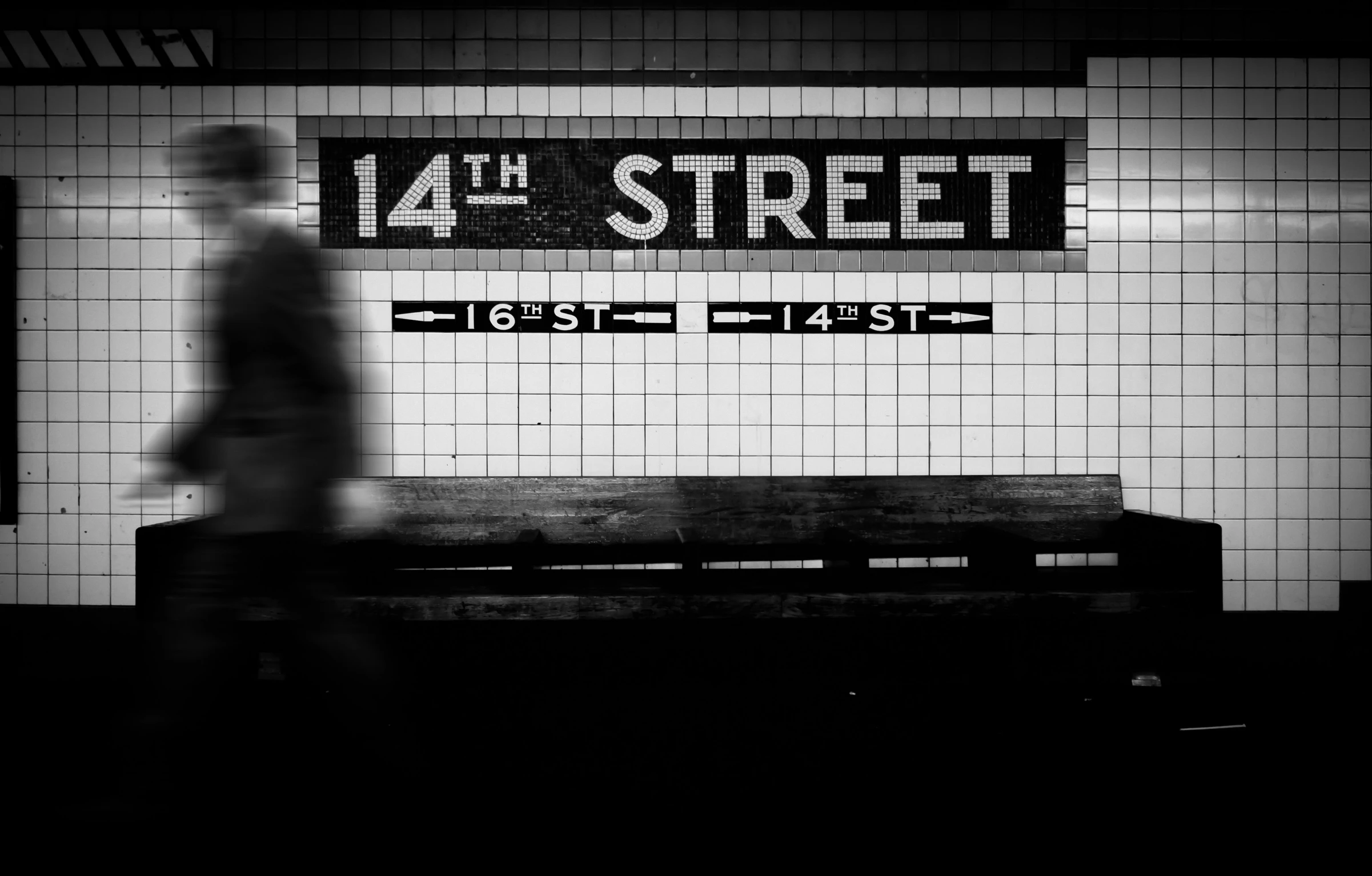 a man walking in front of a subway sign