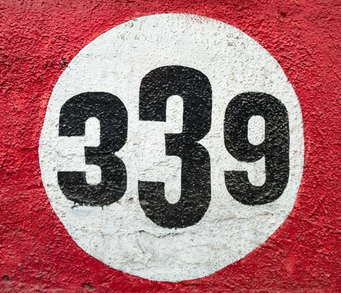 a close - up of a round sign on a red wall with the number 399 painted on it