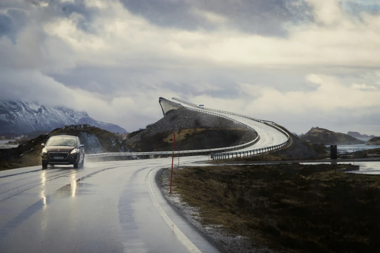 a car driving down the road in front of a mountain