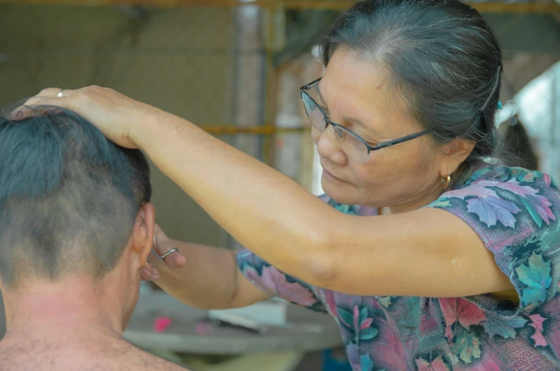 a man combs another mans hair with glasses