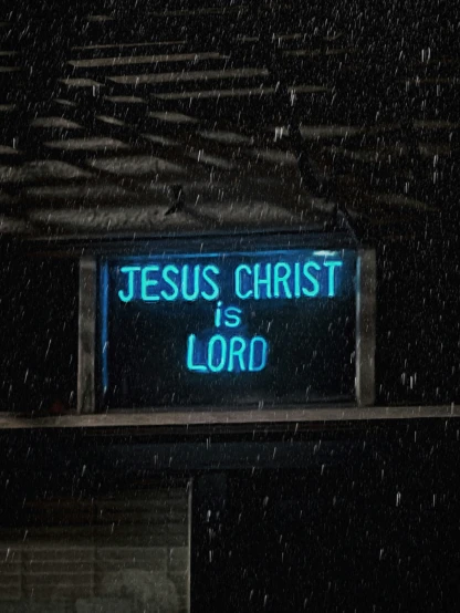 a neon sign that says jesus christ is lord on the outside of a building in the snow