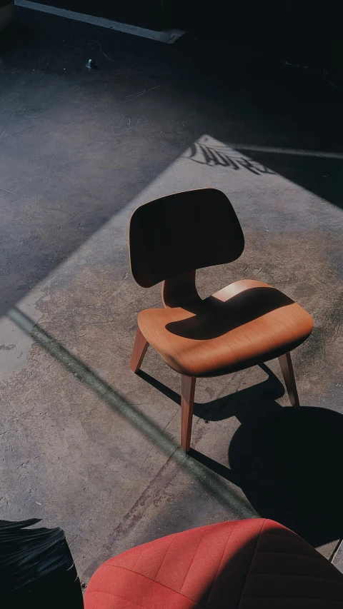 an empty chair on a concrete area next to a luggage bag