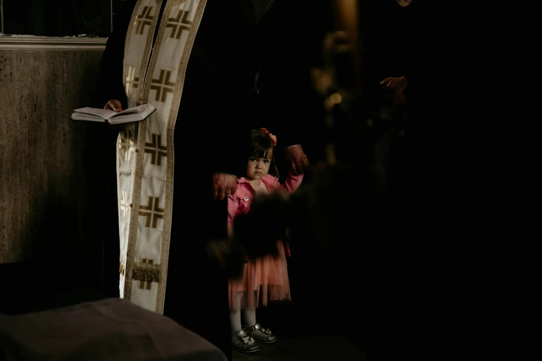 little girl standing at a doorway while holding an object in front of her