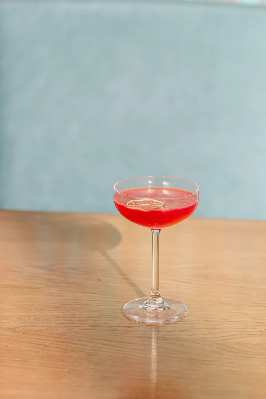 a glass of drink on the table with a blue wall