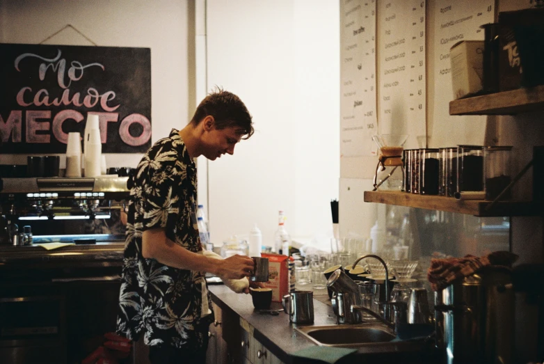 a man standing next to a sink filled with cups