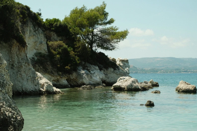 a rocky cliff sits on the side of a body of water