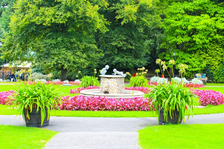 a large garden with pink flowers next to a statue