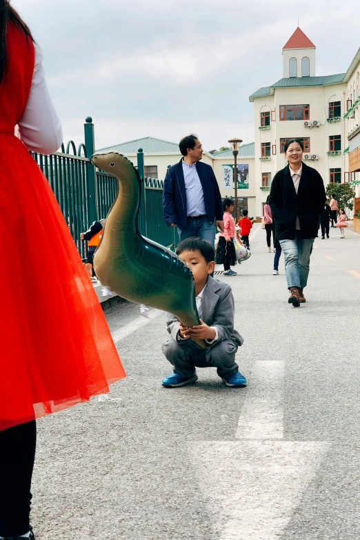 two people are walking down a street while a child plays with an animal