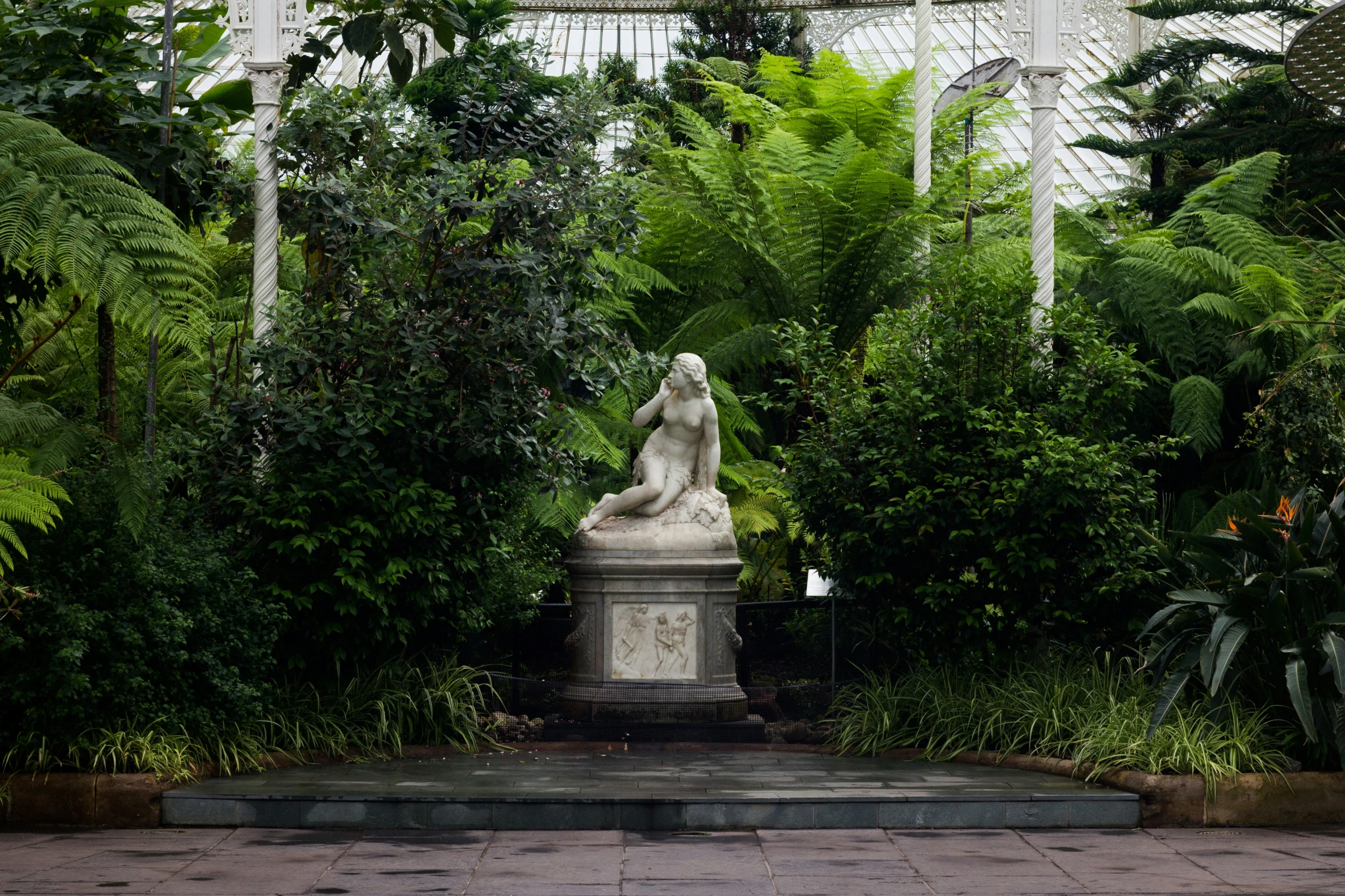 a statue in a courtyard surrounded by lush green plants