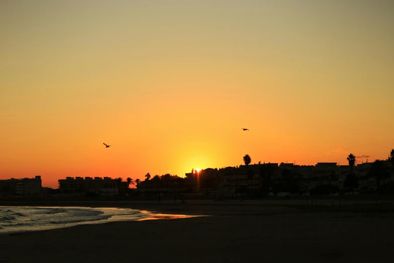 the sun is setting on the horizon at the beach