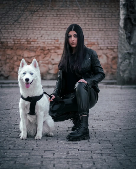 a woman wearing black holding a white dog on a leash