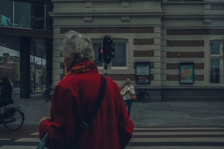 the older woman is crossing the crosswalk with her back to the camera