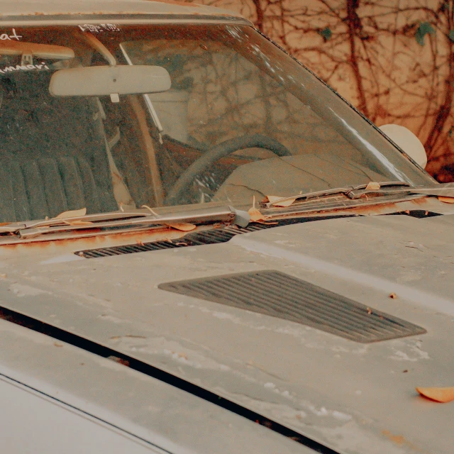 a dirty car's hood is missing a rusted hood