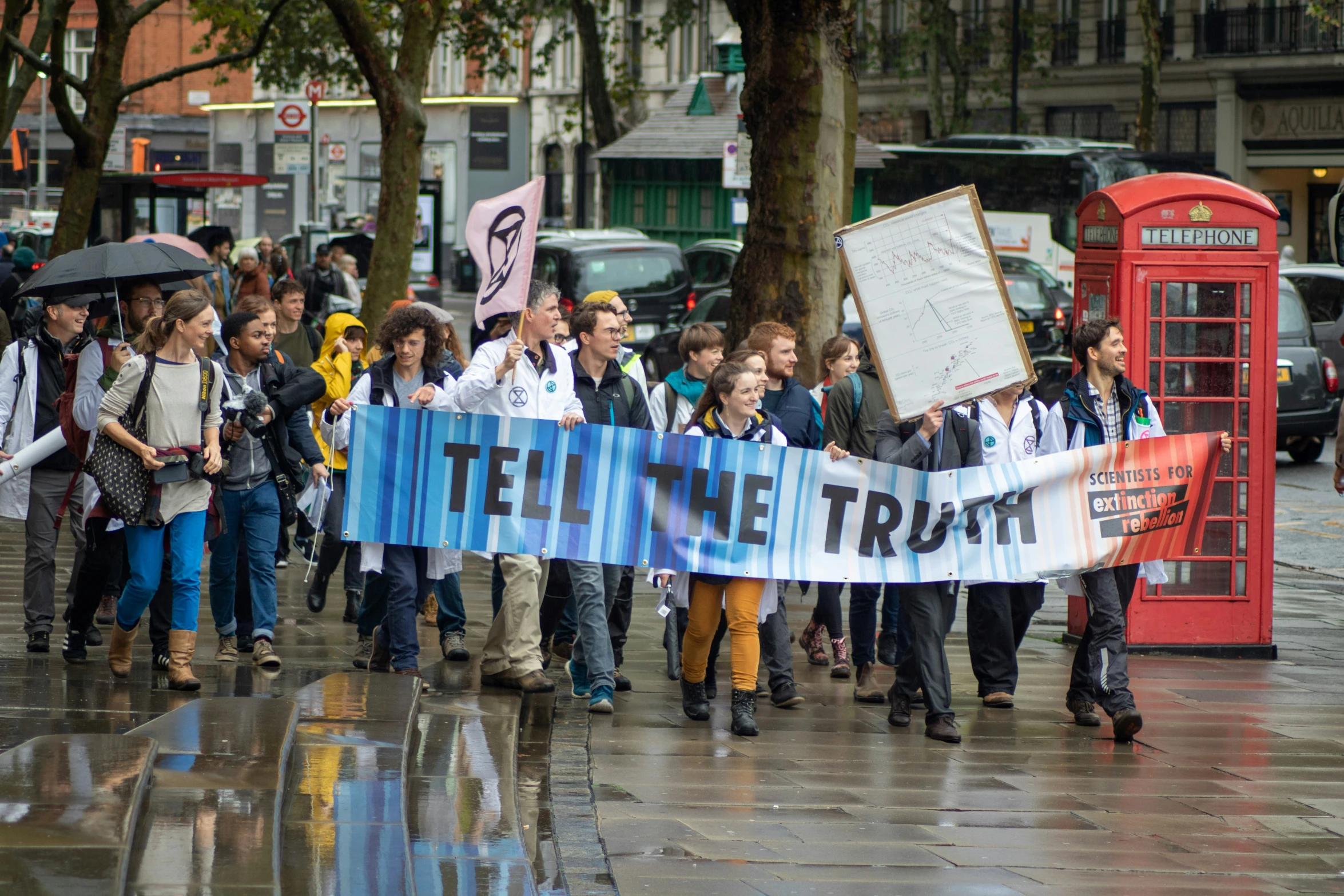 people holding signs with a city scene behind them