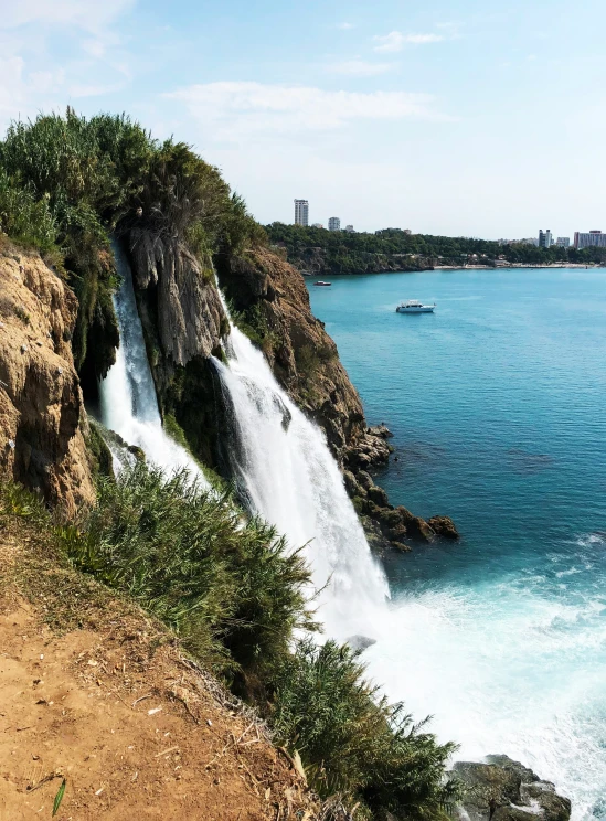 a waterfall is next to the ocean with trees