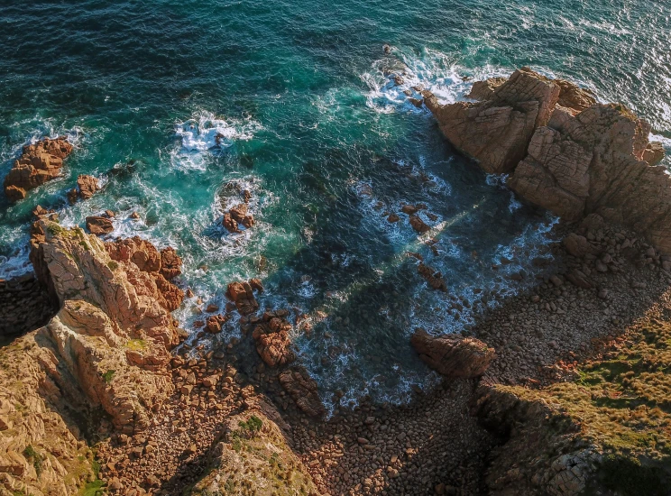 an aerial view of the ocean, rocks, and water