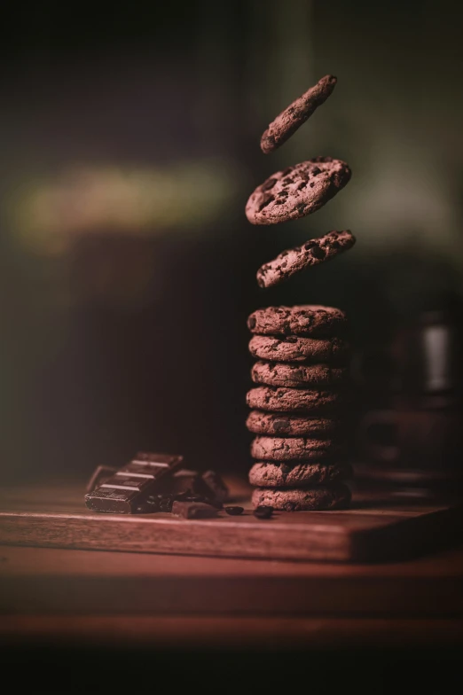 the stack of chocolate chip cookies is next to a few cookies