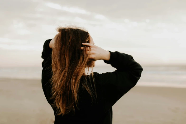 a woman standing on the beach looking into the ocean