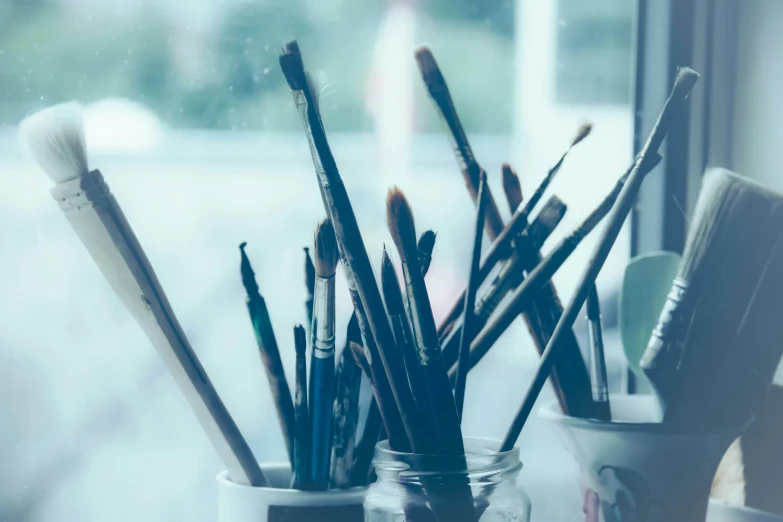 several brushes and paints in a glass jar