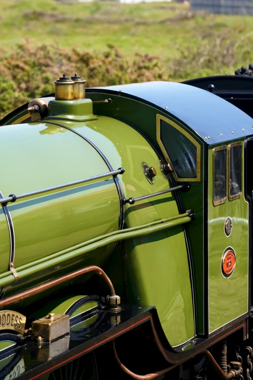 a green and black train engine pulling a green car