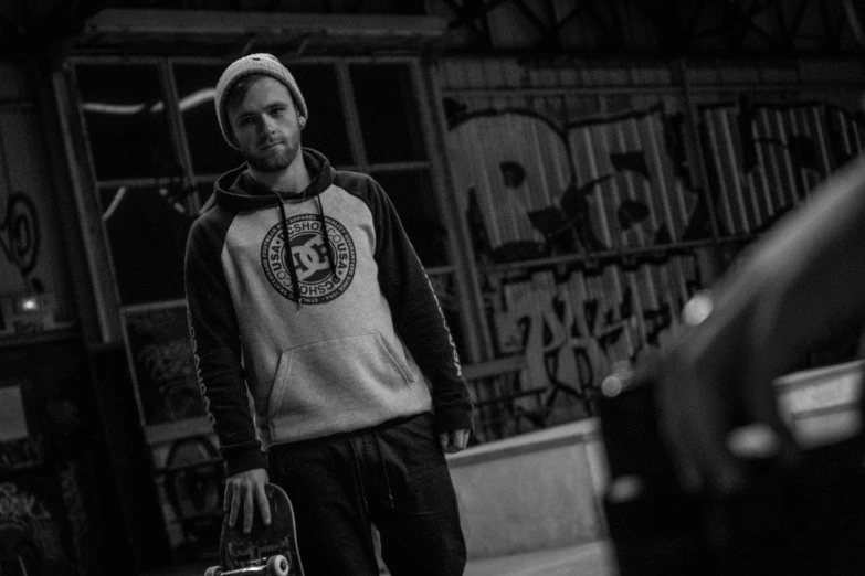 a man standing outside on a street holding his skateboard