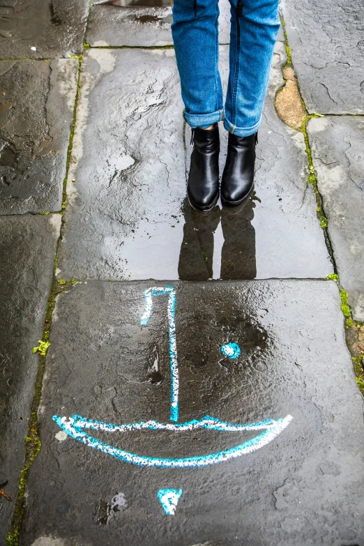 a person with rubber boots standing on the sidewalk