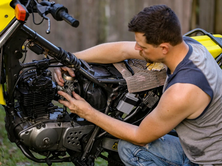 a man working on a motorcycle with a yellow cart in the background