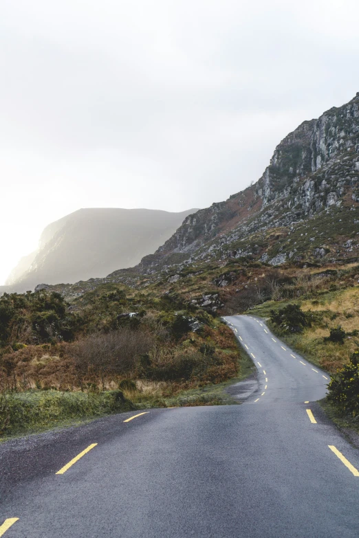 a long curved road next to a tall mountain