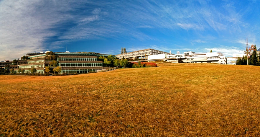 a grassy hill with buildings in the background