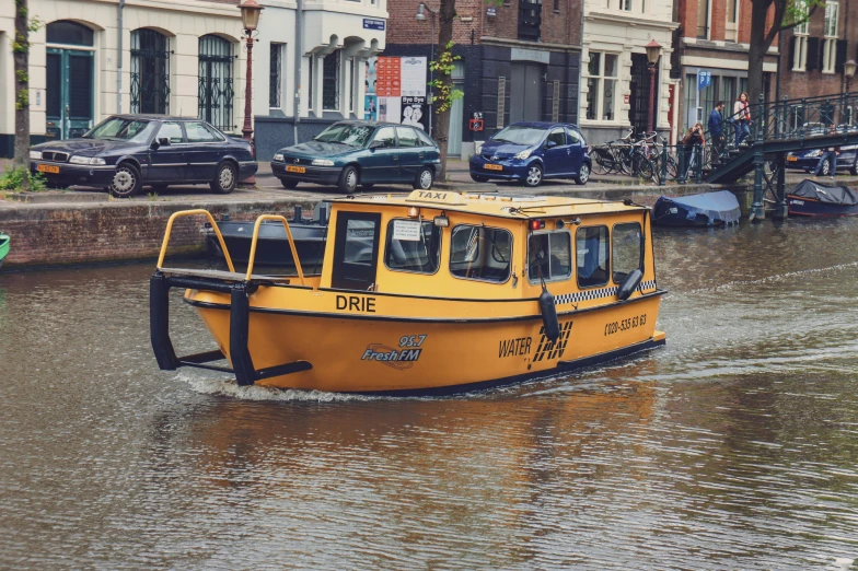 a small yellow boat on a waterway near buildings