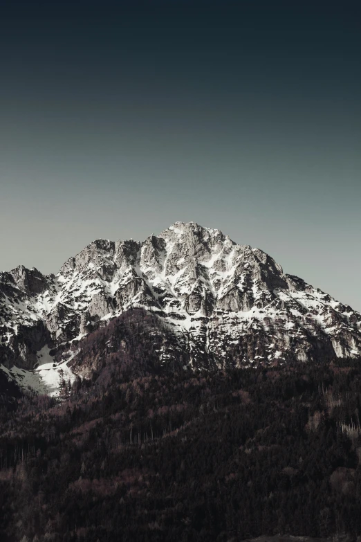 a tall mountain covered in snow and surrounded by mountains