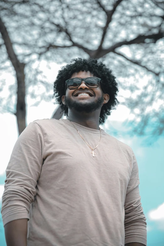 a man with glasses in a park wearing a beige shirt