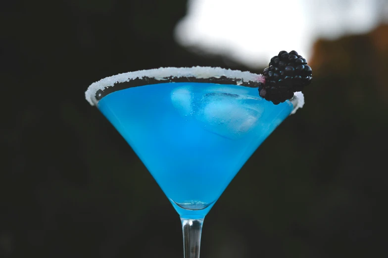 a blue colored drink sitting on top of a glass