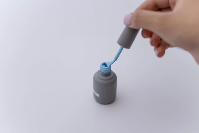 a hand is holding a small bottle that holds an electrical toothbrush