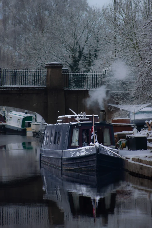 a black boat in the water at a dock with steam coming from it