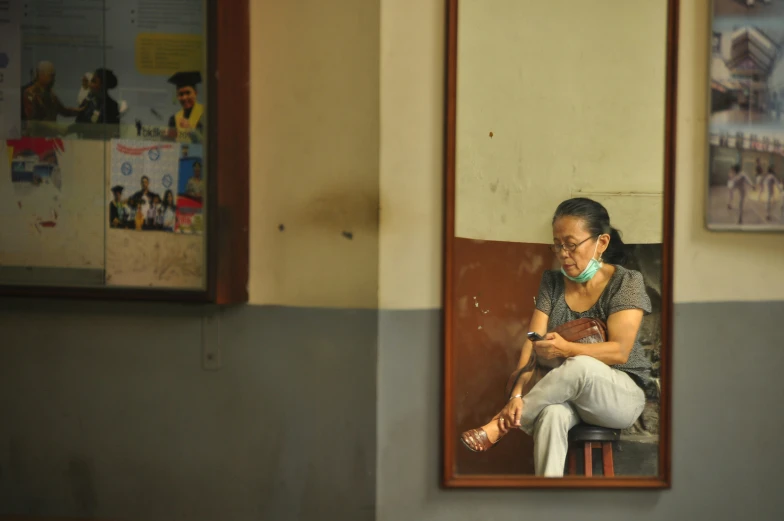 a person sitting at the edge of a doorway looking at their cell phone