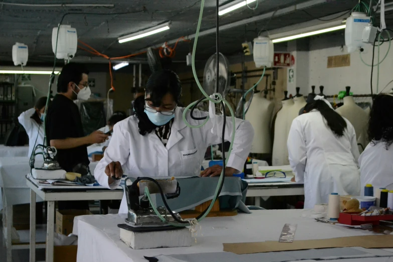 three young women standing at the factory making headphones