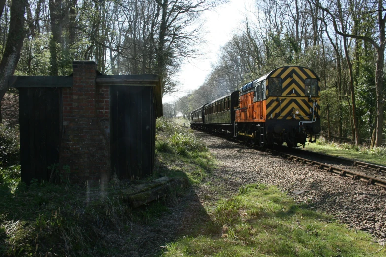 a train is moving through the countryside near a building