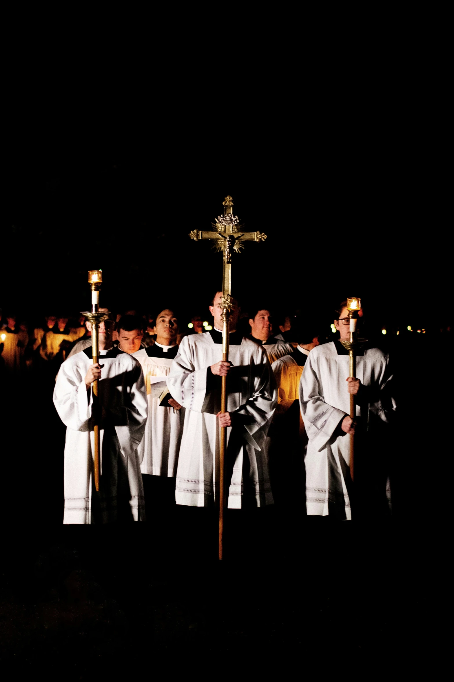 men in white robes holding torches while standing by a cross