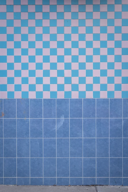 a man sitting on the corner of a tiled wall next to a bench