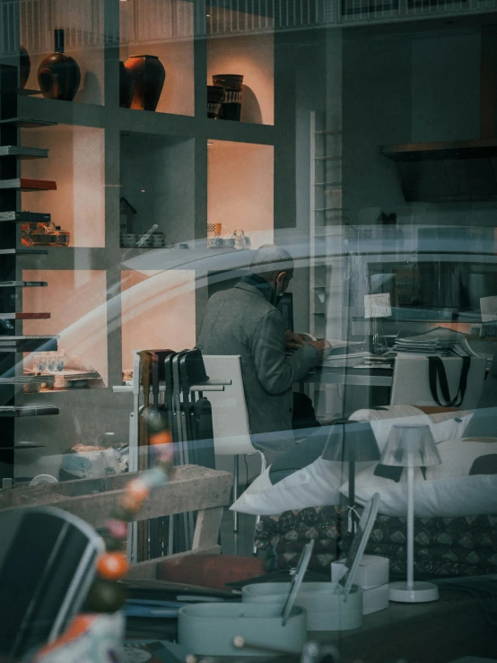 a man standing in the kitchen behind glass looking at soing