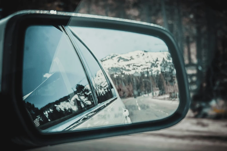 a side mirror showing the road in the mountains