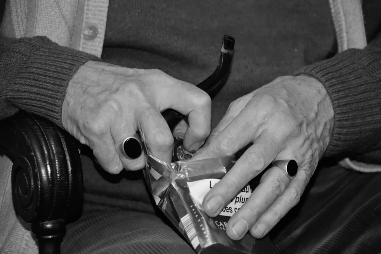 a woman with black nails is peeling a plastic tube