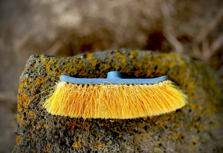 a yellow dust brush sits atop a green stone