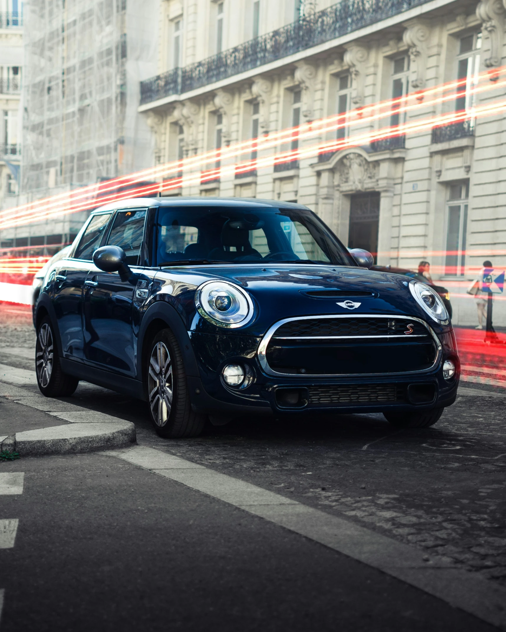 a blue car driving down the road with its headlights on