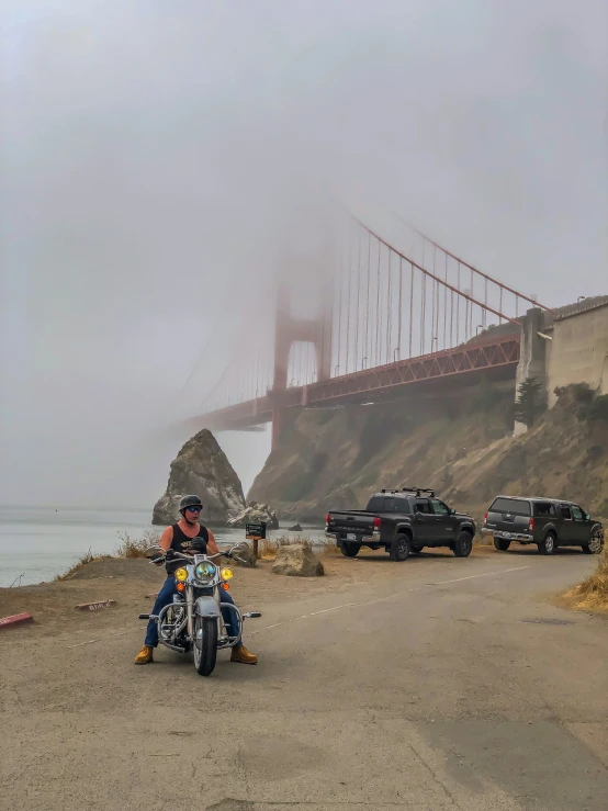 a man is riding his motorcycle near the water and the bridge